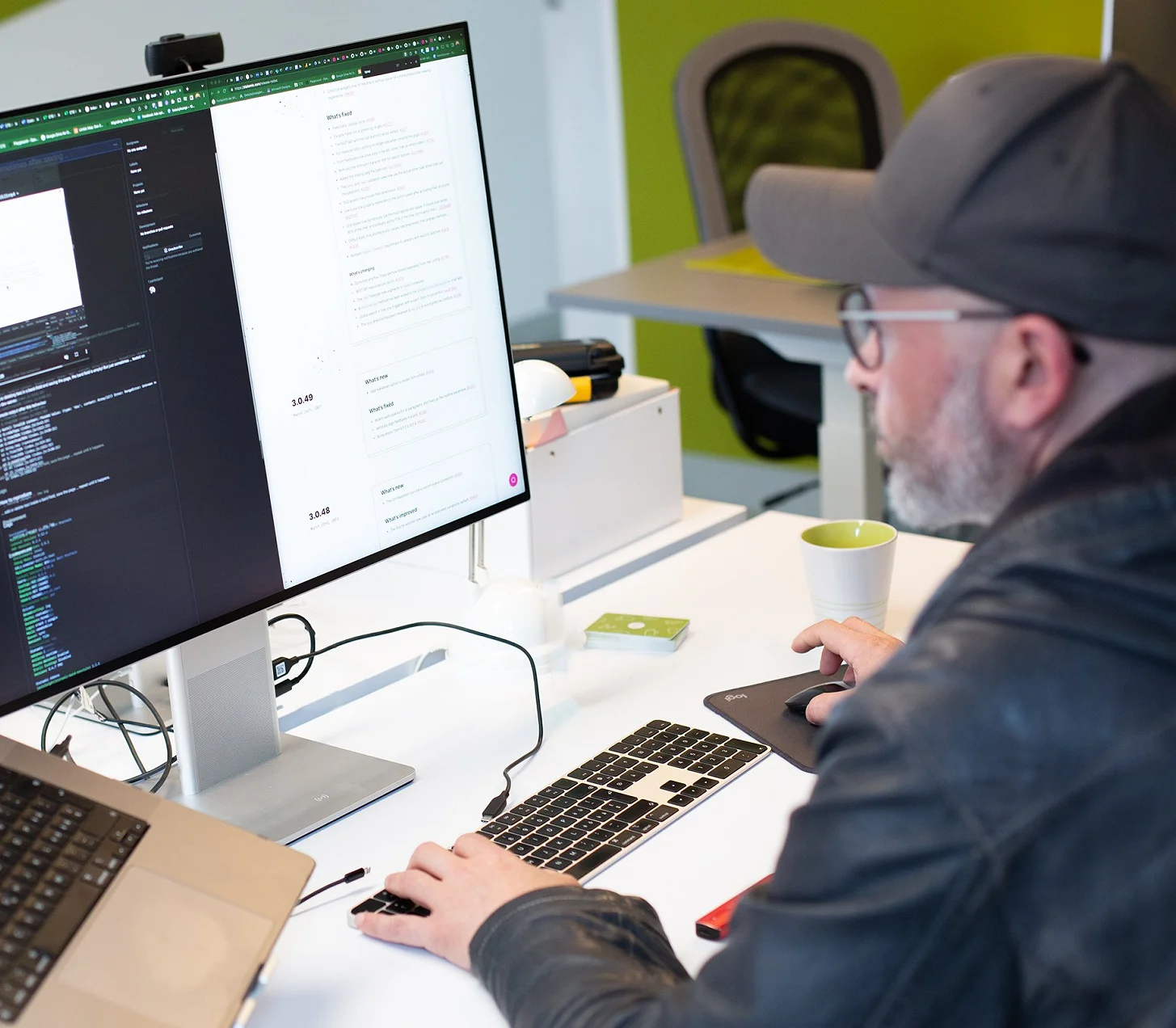 Patrick arbeitet mit Cap am Schreibtisch, auf dem Bildschirm Code und Layout