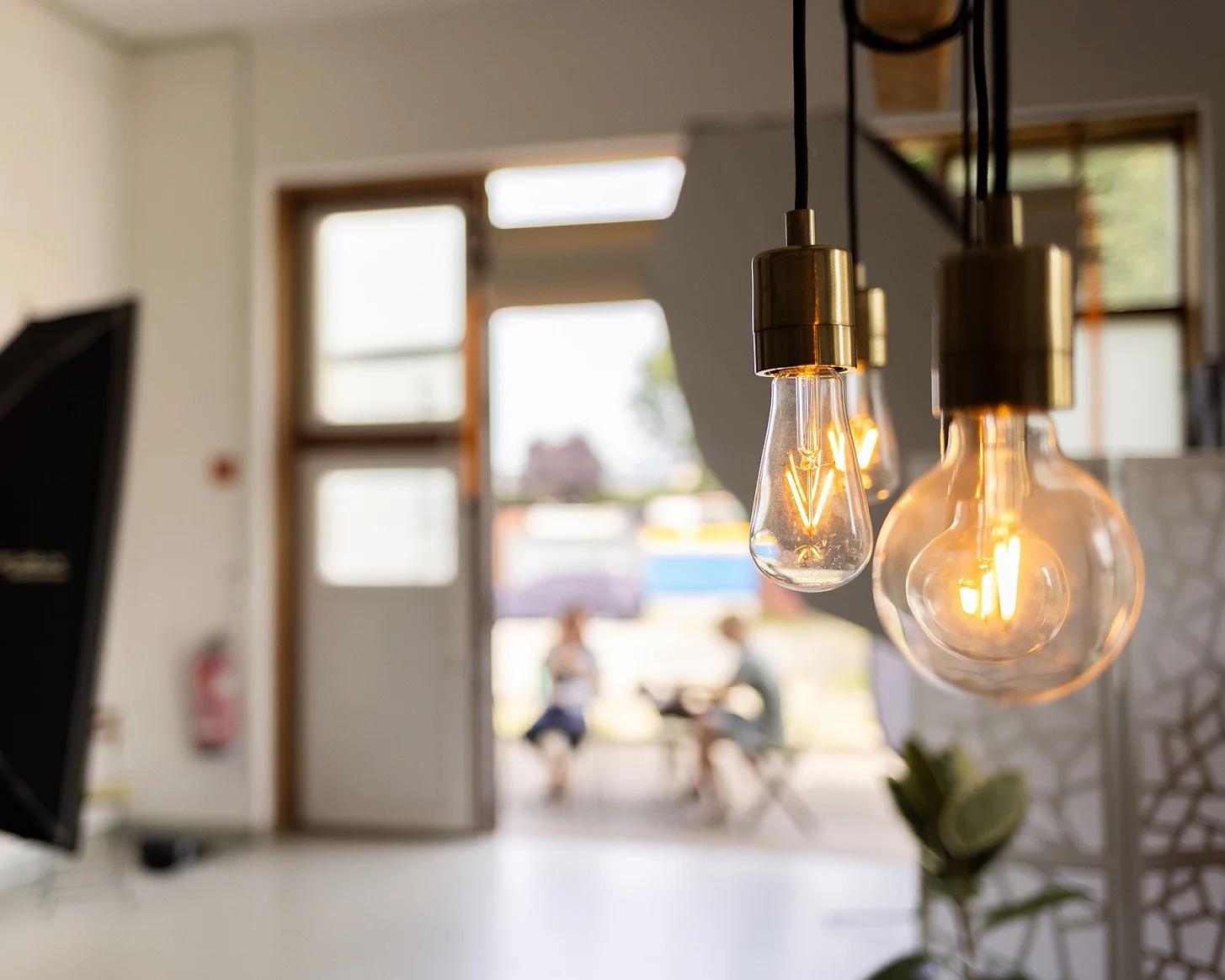 Glühbirnen-Leuchten im Vordergrund, dahinter der Studioeingang mit Softbox