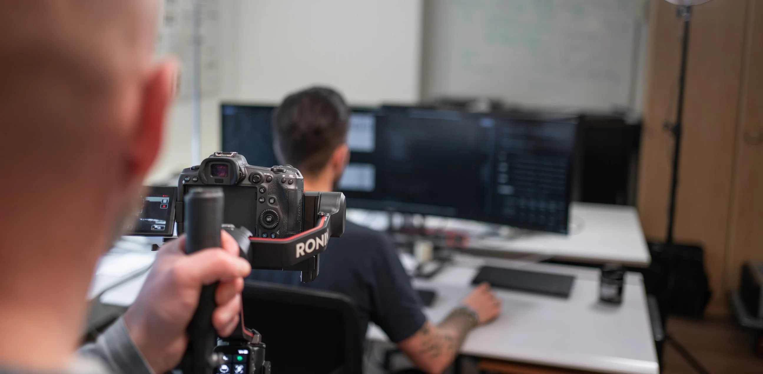 Making-of beim Dreh: Blick über die Schulter auf Kamera und Gimbal, dahinter ein Mitarbeiter am Arbeitsplatz