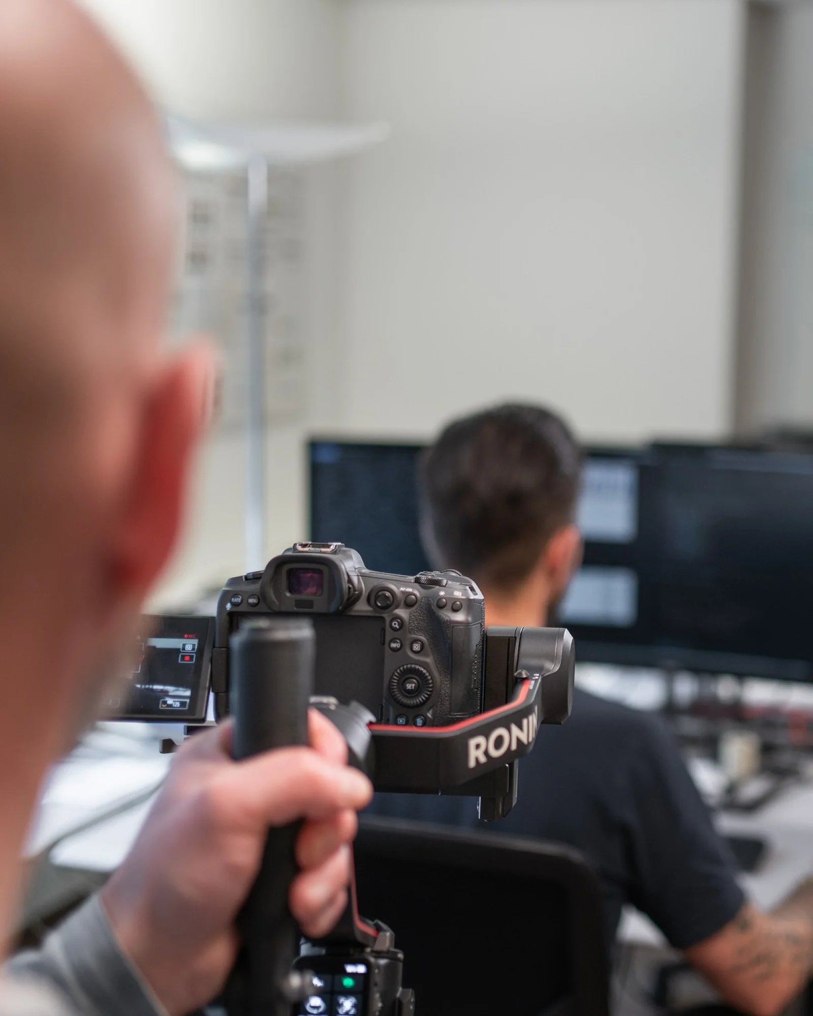 Making-of beim Dreh: Blick über die Schulter auf Kamera und Gimbal, dahinter ein Mitarbeiter am Arbeitsplatz
