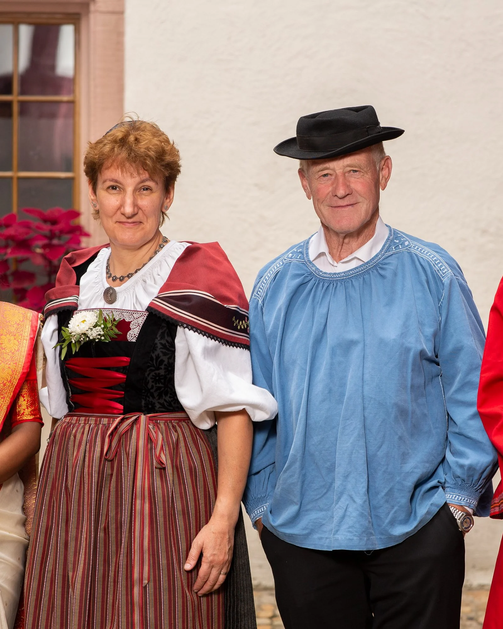 Vier Menschen in Trachten aus verschiedenen Kulturen stehen nebeneinander in einem Innenhof
